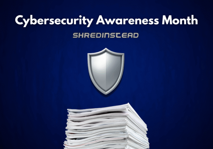 Photograph on a dark blue background with white text at the top reading, "Cybersecurity Awareness Month". Below that, silver text reads, "SHREDINSTEAD". In the center is a silver shield icon, and at the bottom is a large stack of white papers.